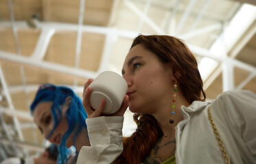 Two young LGBT females buying aroma candles at a flea market. Young diverse woman smelling a hand...