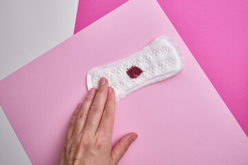 Menstrual pad with red sequins on a pink background. The period of the menstrual cycle, feminine...