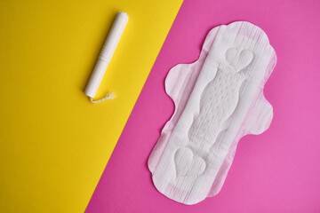 Women's pads and tampon. Sanitary pads lie next to a tampon on an isolated background on a pink and white background. The concept of health, feminine hygiene and the menstrual cycle