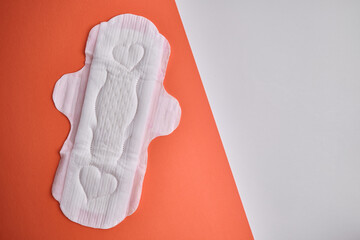 Women's pads and tampon. Sanitary pads lie next to a tampon on an isolated background on a pink and white background. The concept of health, feminine hygiene and the menstrual cycle