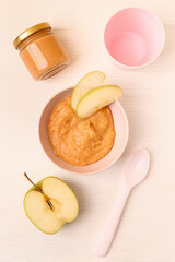 Bowl of apple baby puree on light background