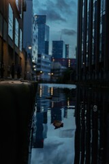 Vertical shot of the reflection of modern buildings on the ground after rain in the evening