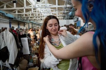 LGBT couple buying fashion accessories at a flea market. Two young lesbian women shopping. Portrait of a cheerful diverse women buying vintage stuff in a thrift shop
