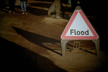Closeup shot of a triangle sign with the text "Flood" on the street