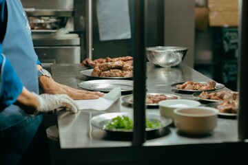 View through a window of a chef preparing a meal with meat