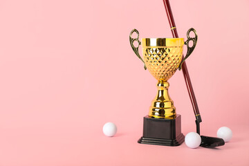 Gold cup with golf club and balls on pink background