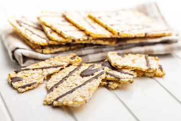 Puffed corn crackers chocolate covered on white table.