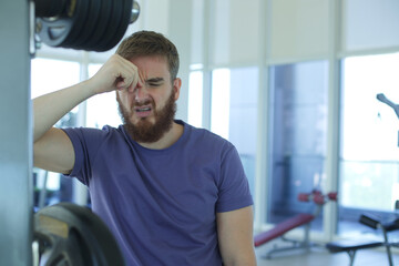 Portrait of tired exhausted sad man unhappy guy in the gym, feeling bad during training 