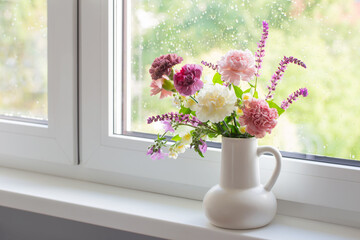 pink and purple summer flowers in white jug on windowsill