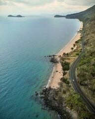 Drone shot of an asphalt road at the mountain foot rocky coast by the sea