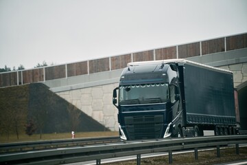 A big truck moves on the highway concept of the shipping company. Landscape with a moving European semi truck
