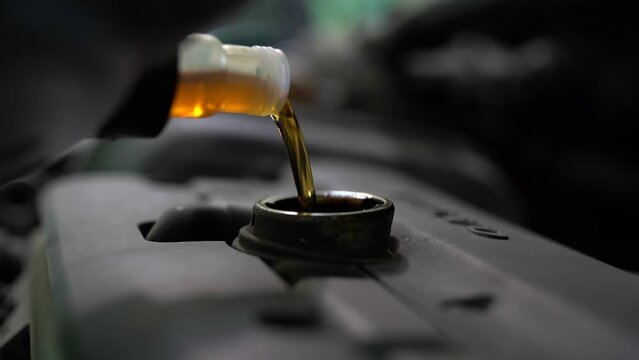 Pouring oil to car engine, close up