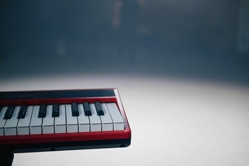 A keyboard in the spotlight is illuminated by the spotlight above. The piano is red