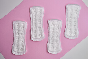 Women's pads and tampon. Sanitary pads lie next to a tampon on an isolated background on a pink and white background. The concept of health, feminine hygiene and the menstrual cycle