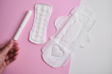 Women's pads and tampon. Sanitary pads lie next to a tampon on an isolated background on a pink and white background. The concept of health, feminine hygiene and the menstrual cycle