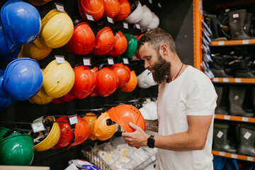 Fototapeta premium A man chooses a helmet in a hardware store.