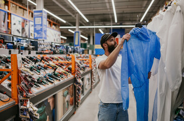 Fototapeta premium A man chooses a protective suit in a hardware store.