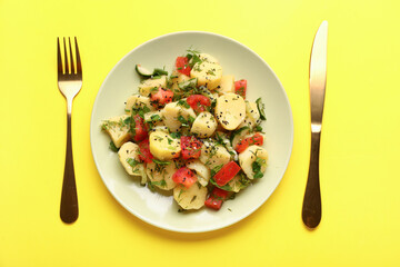 Plate of tasty Potato Salad with vegetables on yellow background