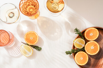 Fototapeta na wymiar Oranges lemons rosemary, citrus fruits on a wooden plate shadow of a palm leaf. Summer citrus background.