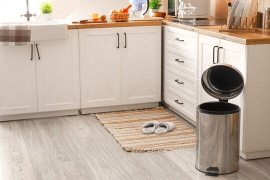Opened metallic trash bin on floor in modern kitchen