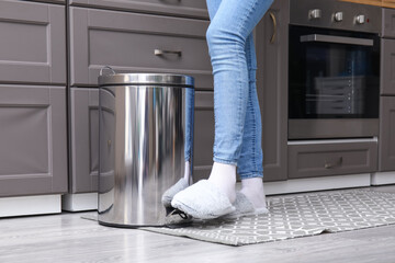 Woman opening trash been with her foot in modern kitchen