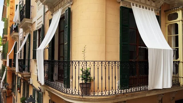 Beautiful Balcony Door With Green Shutter and White Sun Protection Curtain in Palma de Mallorca.