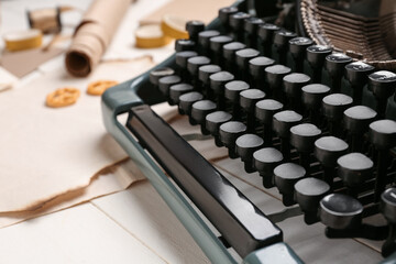 Vintage typewriter with parchments on white wooden table, closeup