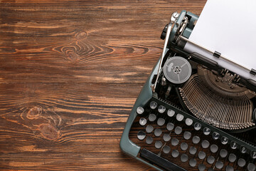 Vintage typewriter with blank paper sheet on wooden table