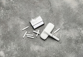 Modern electronic cigar and pack of sticks on grey grunge table