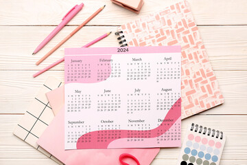 Calendar, notebooks, color palette and stationary on white wooden background