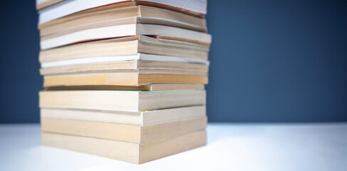 stack of books on white table and dark blue background.