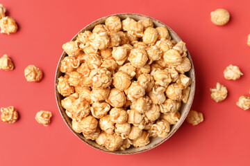 Bowl with crispy popcorn on red background