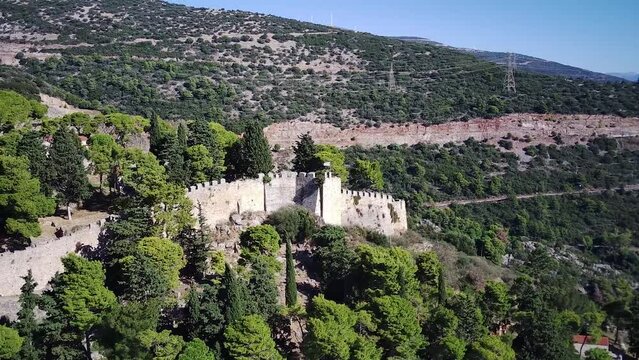 Drone pull-out view of the Venetian Castle of Nafpaktos on the hilltop covered in trees