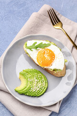 Plate of tasty bruschetta with avocado and egg on grey background