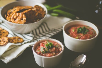 Closeup shot of cups of tomato salsa and nachos in a white bowl