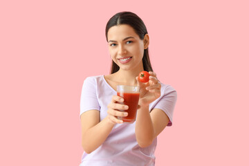 Young woman with glass of vegetable juice and tomato on pink background