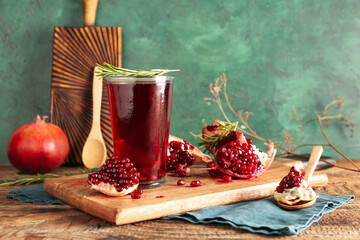 Board with glass of fresh pomegranate juice on wooden table