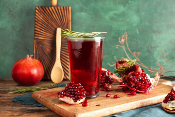 Board with glass of fresh pomegranate juice on wooden table