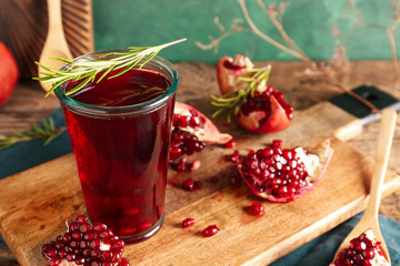 Board with glass of fresh pomegranate juice on wooden table