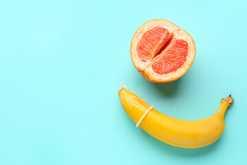 Banana with condom and half of grapefruit on blue background. Sex concept - obrazy, fototapety, plakaty