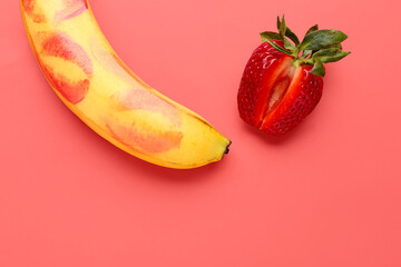 Banana with lipstick kiss marks and strawberry on red background. Sex concept