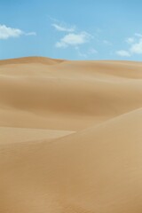 Vertical shot of a an empty desert dunes under a blue sky