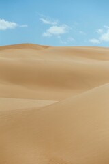 Vertical shot of a an empty desert dunes under a blue sky