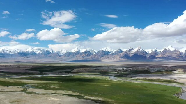 Time-lapse view of snow-capped mountains and steppes of the Pamirs under cloudy sky
