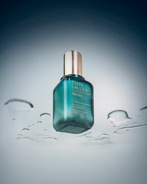 Vertical shot of an Estee Lauder skin serum on a wet glass surface