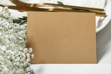 Blank invitation card and gypsophila flowers on white table, closeup