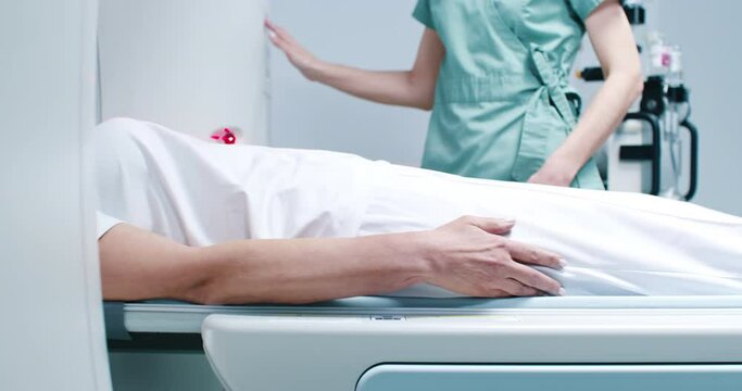 Shoot from side of woman after magnetic resonance imaging. Patient is moving out of CT scanner bed. Nurse manages MRI examining. Female gets out of MRI moving bed. Woman is finished scanner procedure.