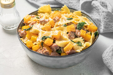 Autumn pasta farfalle with sausage, spinach and pumpkin