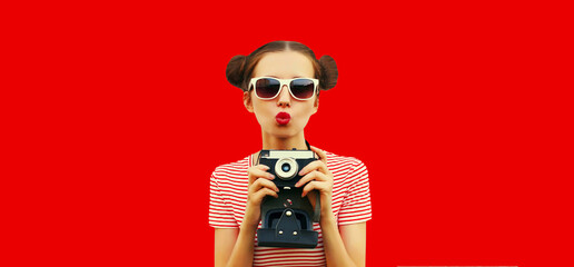 Portrait of happy young woman photographer with film camera, female with cool girly hairstyle on red background - obrazy, fototapety, plakaty