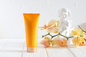Mockup cream tube, yellow bottle and orchid flower, place for text